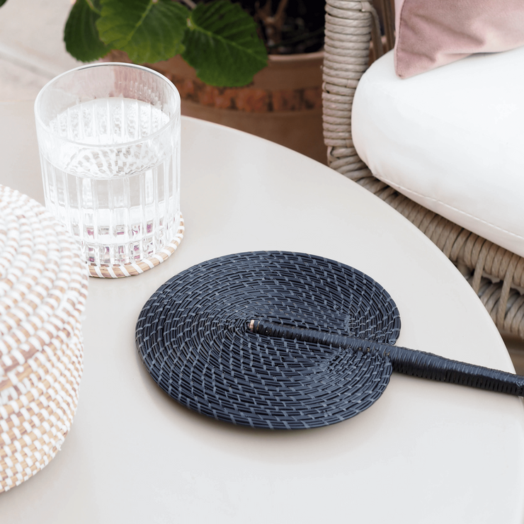 La Basketry fan in black woven with recycled plastic displayed on a garden table