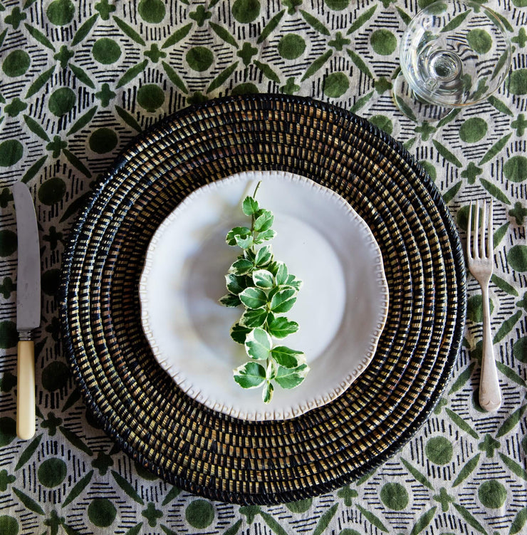 a hand-woven curved lap tray in black by la basketry on a tablecloth and next to some cutlery