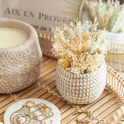 Handwoven La Basketry mini basket in white and natural with dried flowers inside, set on a wooden tray and surrounded by gold jewellery, a candle and a marble coaster.