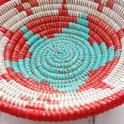 la basketry anta storage bowl close up in red white and turquoise with beautiful woven star pattern, handmade by artisans in senegal